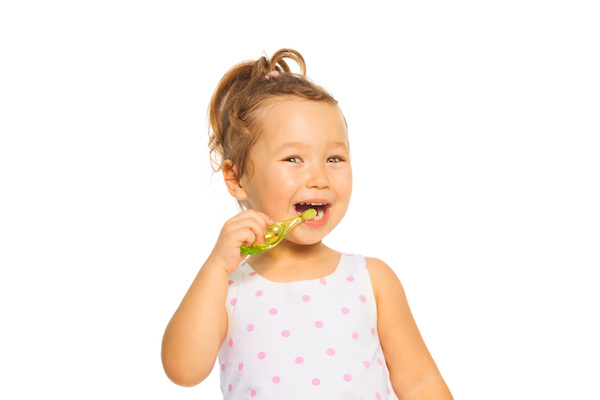 Cute little Asian girl cleaning teeth with toothpaste standing isolated on white