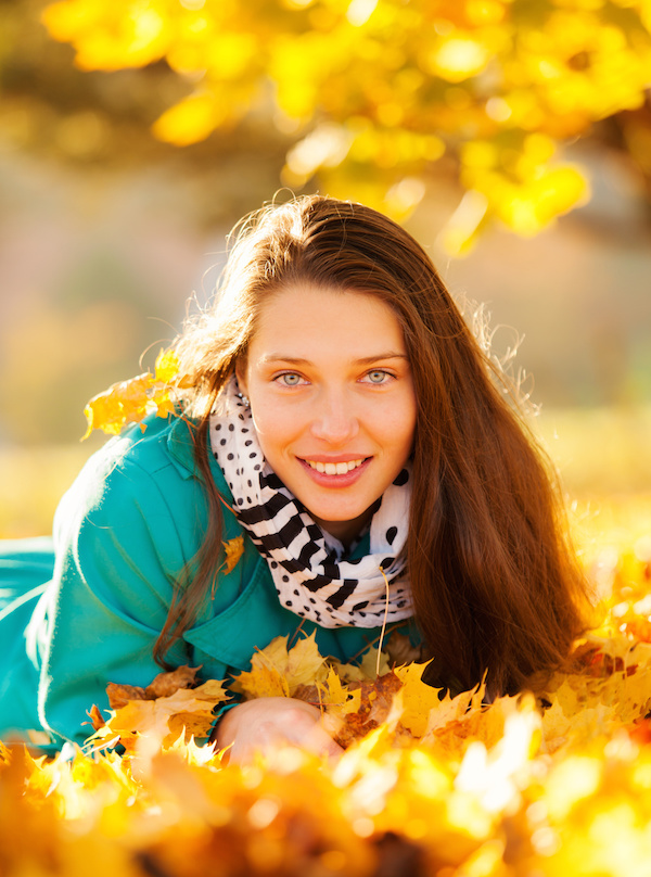 Beautiful brunette girl lying in autumn leaves with smilling face. Concept of happiness and joy