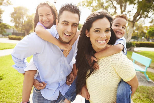 Parents Giving Children Piggyback Ride In Garden