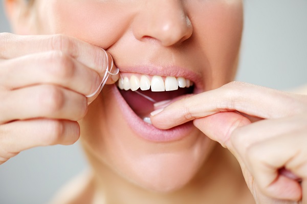 woman cleaning tooth with floss