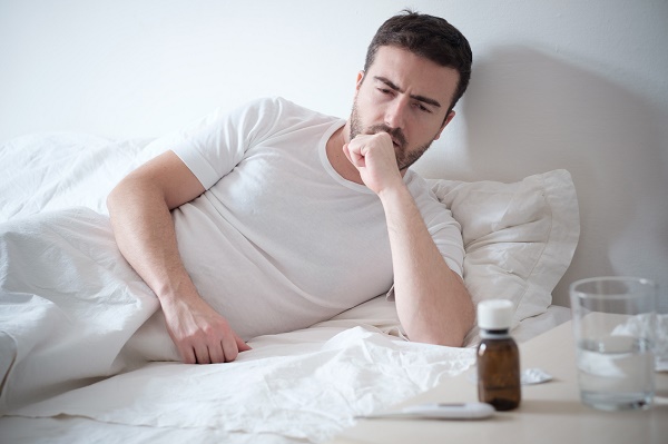 Man feeling bad lying in the bed and coughing