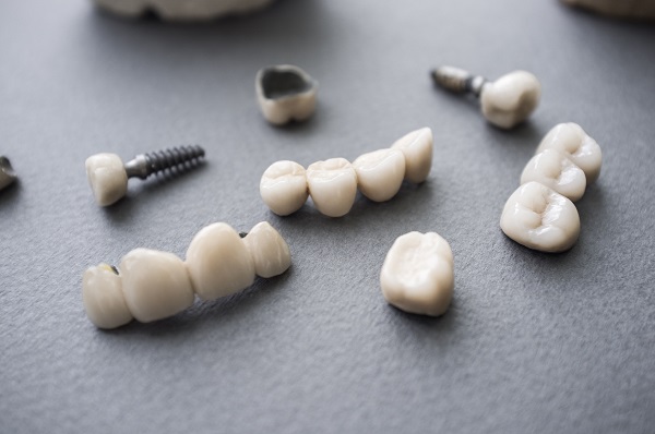 Ceramic dentures and crowns on gray background. Top view on set of single dentures and dental crowns. Tooth repair equipment on gray background.