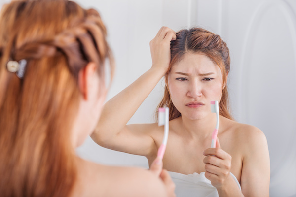 unhappy woman in bath towel brushing teeth with mirror in the bathroom