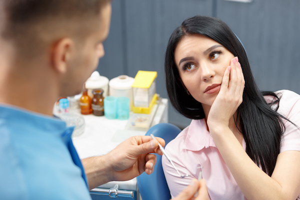 Girl patient goes to the dentist with a toothache in the dental office. Young woman holding the hand of a sick tooth