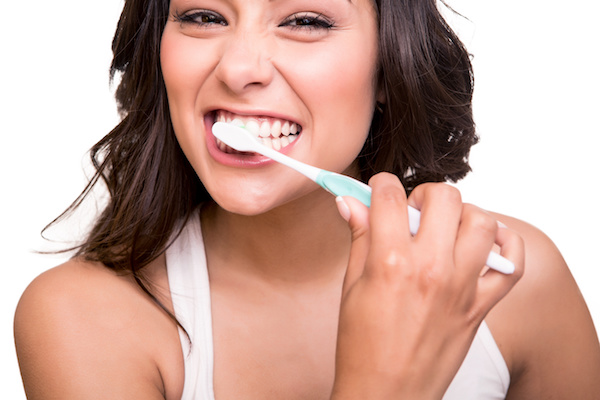 Smiling young woman with healthy teeth holding a tooth brush