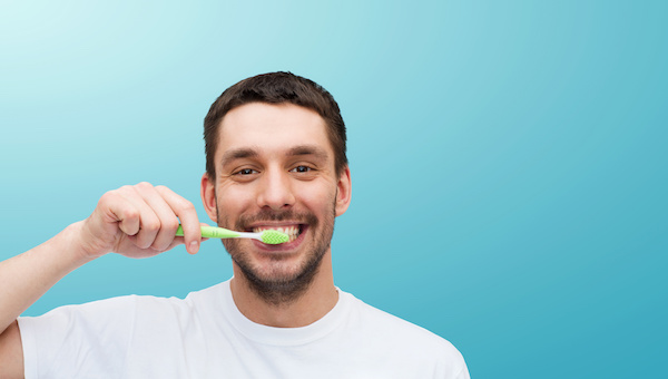 health and beauty concept - smiling young man with toothbrush