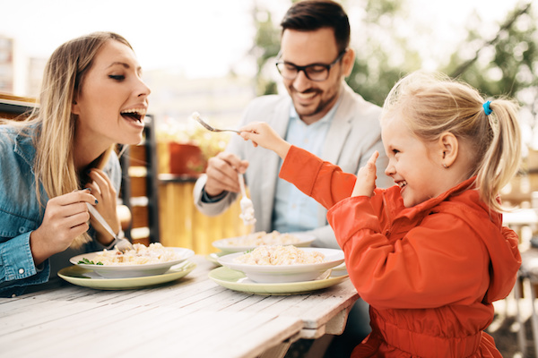 Happy family is enjoying pasta in restaurant.