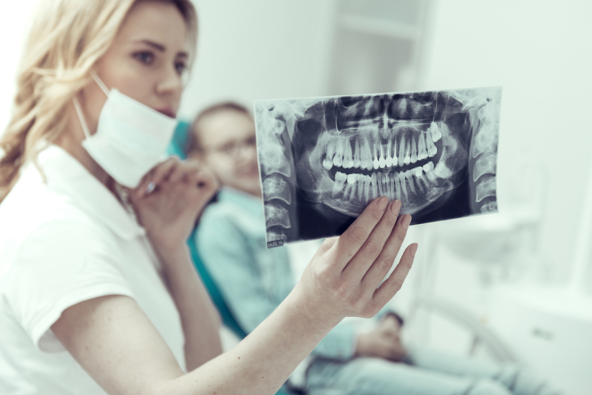 Good teeth. Professional young dentist studying the X-ray of a girls jaw