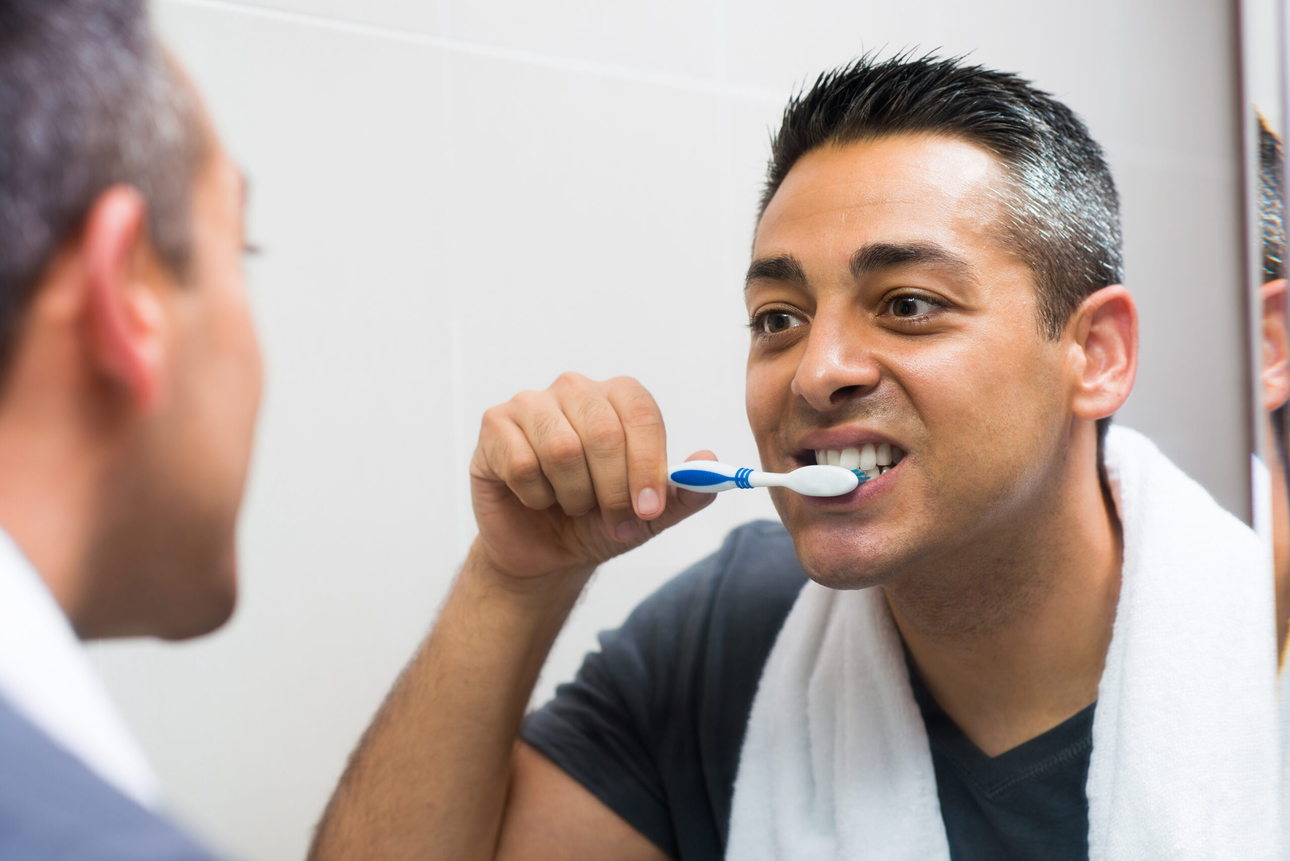 periodontal disease Closeup image of a man brushing his teeth while looking in the mirror in the apartment on the foreground