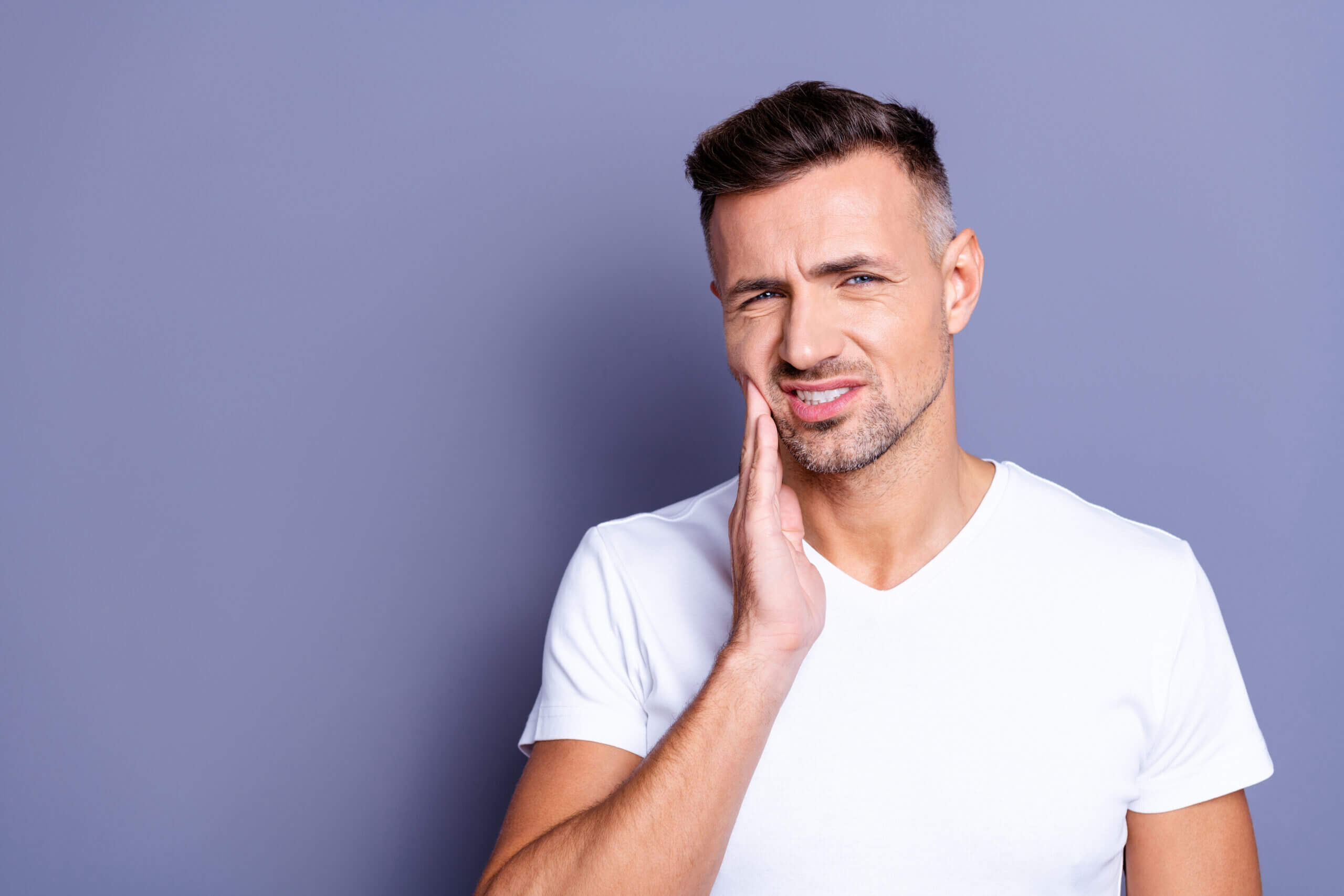 crack a tooth Close up photo amazing he him his middle age macho hand arm hold cheekbone, teeth terrible pain injury sadness cry facial expression weakness wear casual white t-shirt isolated grey background