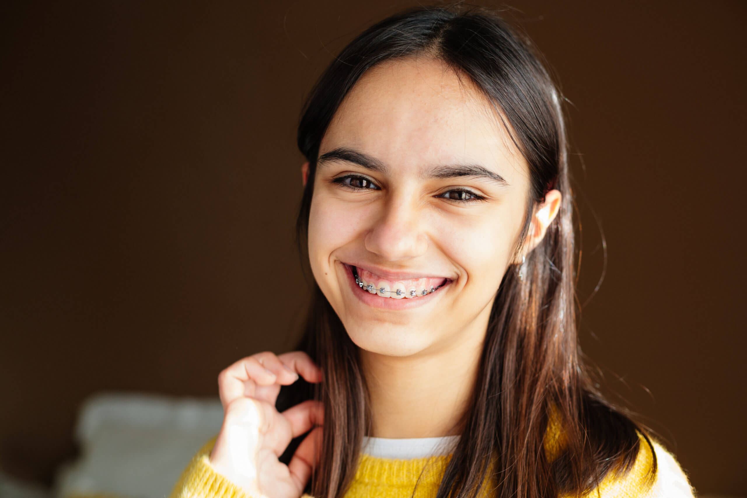 Portrait of a happy teen girl with braces and some acne smiling at home with the sun coming through the window