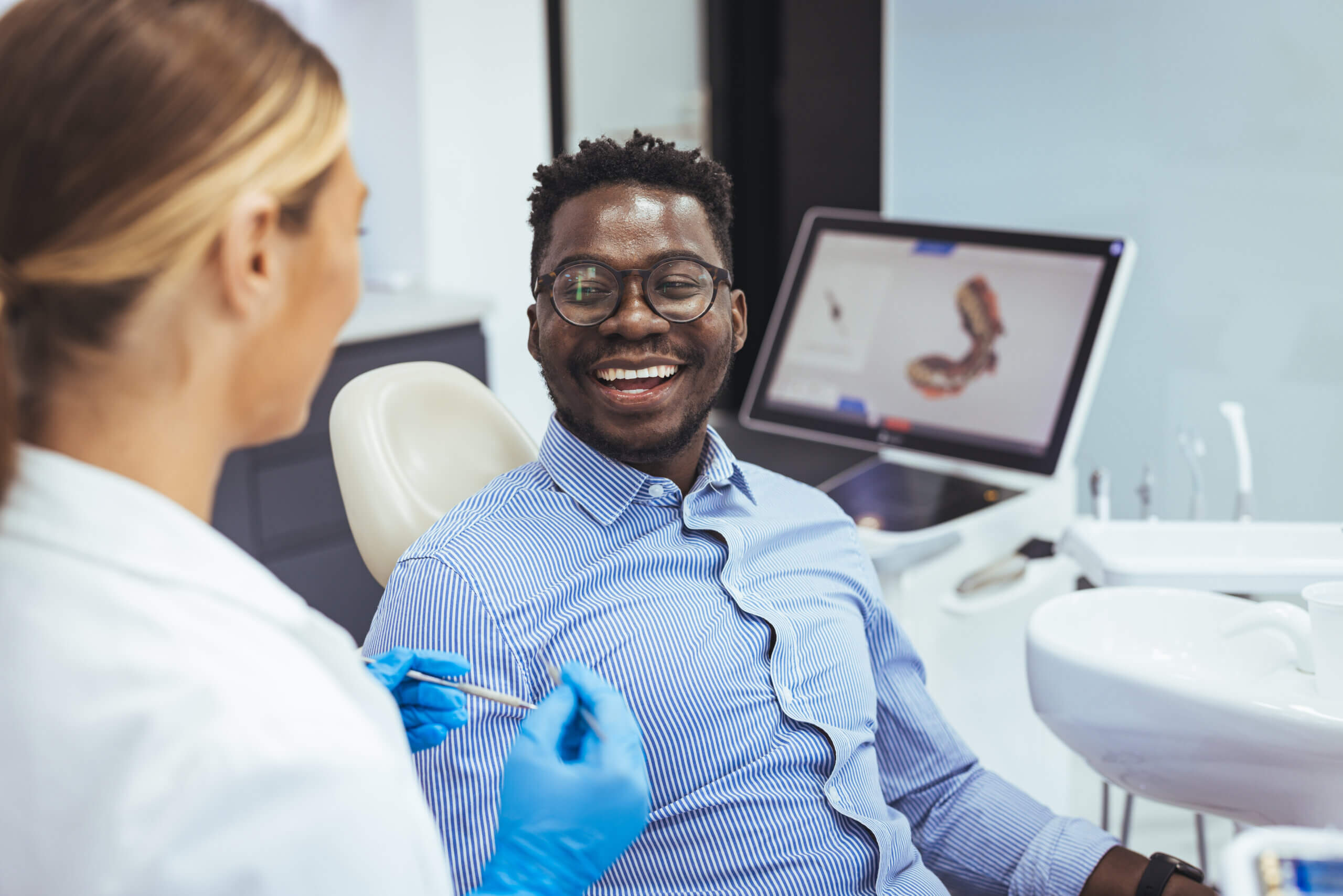 African American young man having a visit at the dentist's. He is sitting on chair at dentist office in dental clinic.. Happy dentist and patient in dentist's office. My dentist is the best!